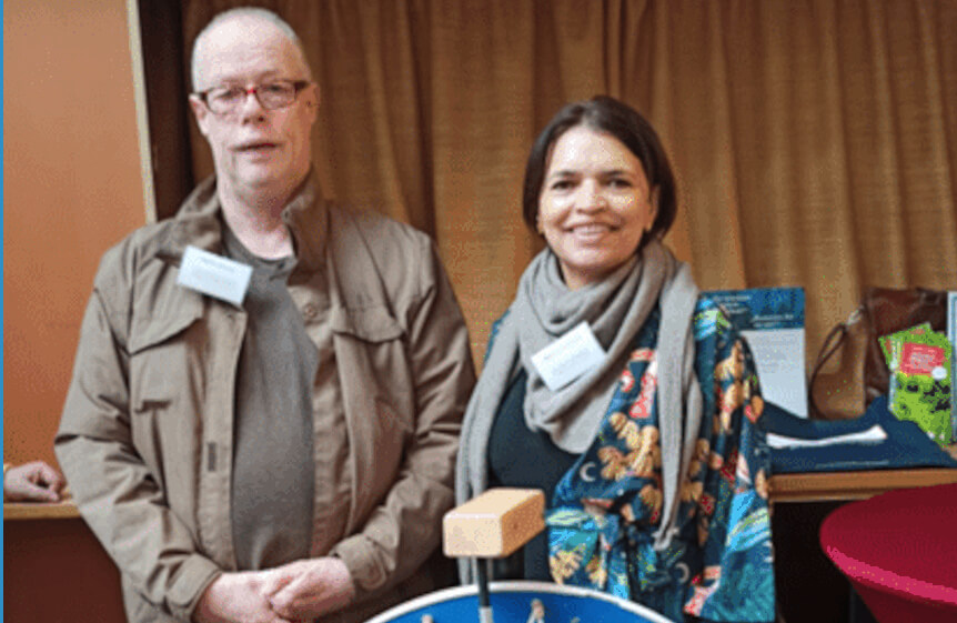 Das Glücksrad des Sprachbrücke-Hamburg e.V., dahinter zwei Menschen