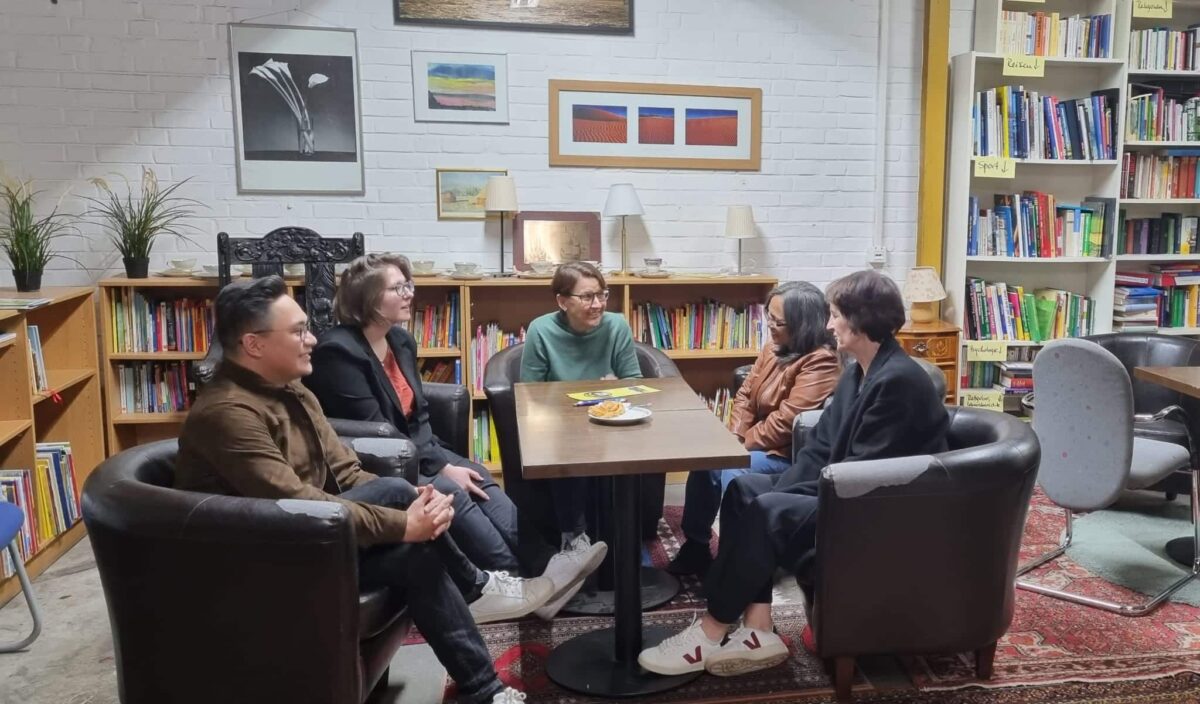 Mehrere Personen sitzen um einen Tisch herum in einer Art Bibliothek