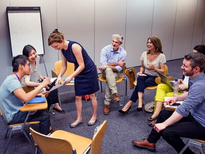 6 Personen im Stuhlkreis einer Frau in der Mitte