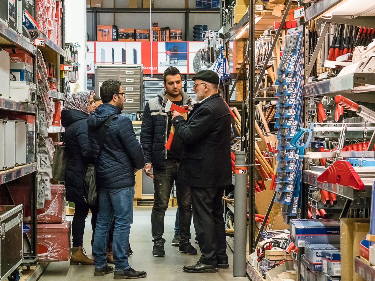 Mehrere Männer stehen in einem Lager und unterhalten sich